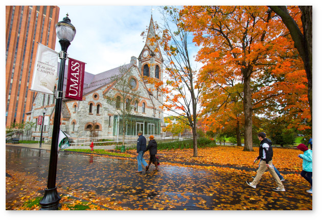 Bright orange fall leaves on the trees and on the ground dominate this rainy day scene of students walking by the Old Chapel and library.
