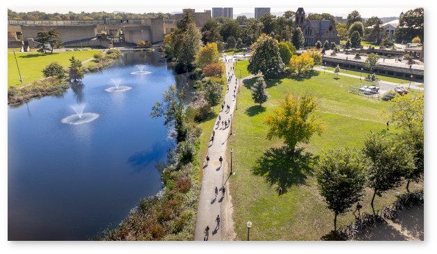 Aerial view of campus in daylight. Campus pond on the left with a grassy area on the right